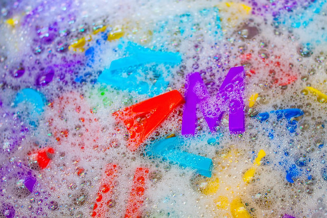 cleaning toy letters in soap and water to disinfect them