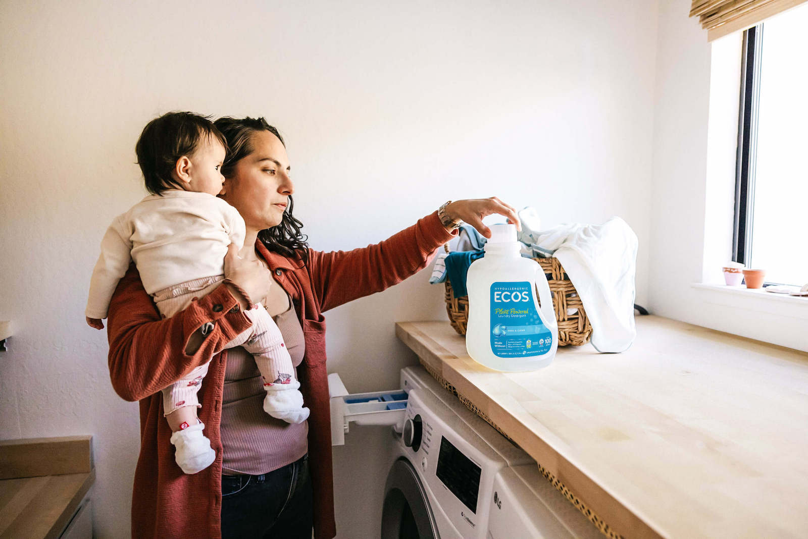 Mother Holding Baby While Doing Laundry
